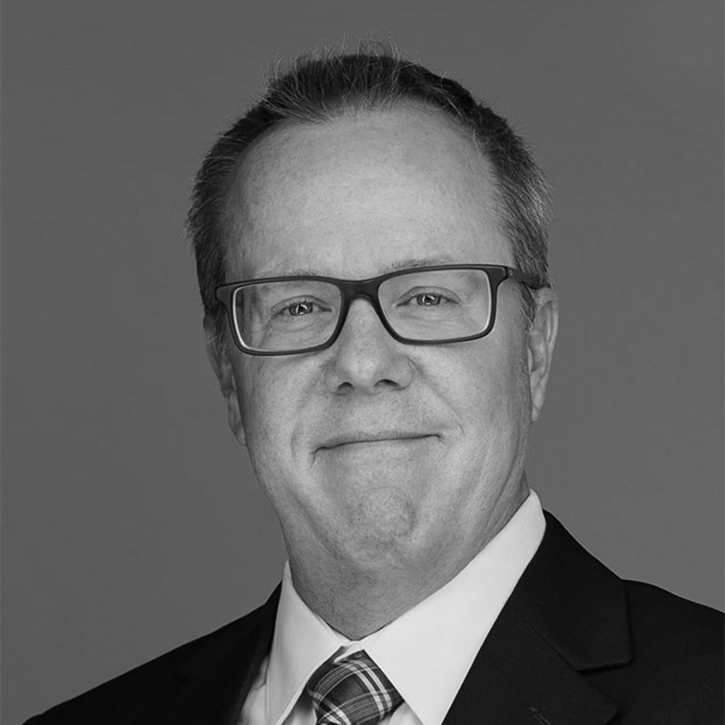 Black-and-white headshot of man in suit and glasses