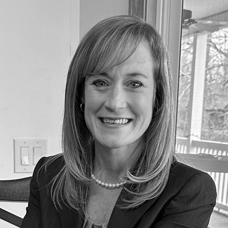Smiling woman in blazer and pearl necklace indoors