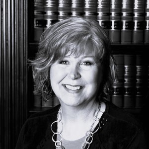 Black-and-white portrait of smiling woman before bookshelves