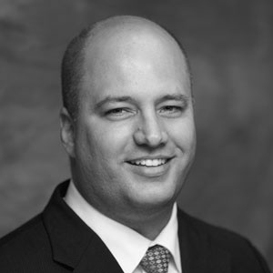 Black-and-white headshot of smiling man in suit