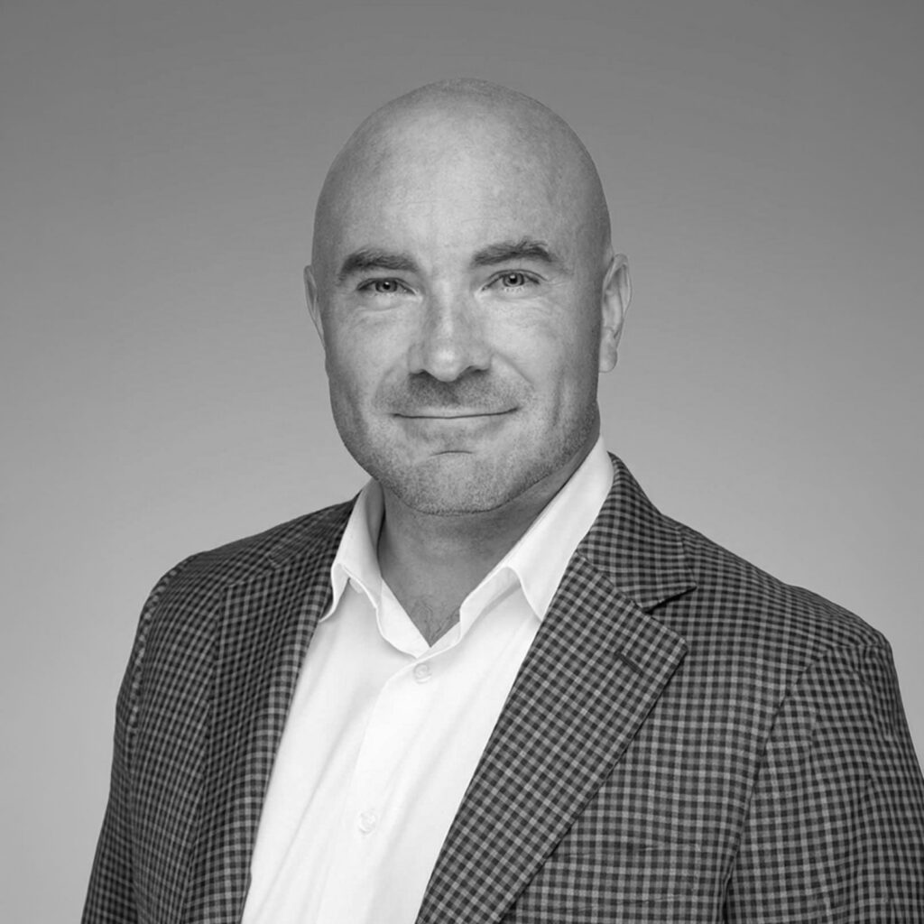 Black-and-white headshot of bald man in blazer