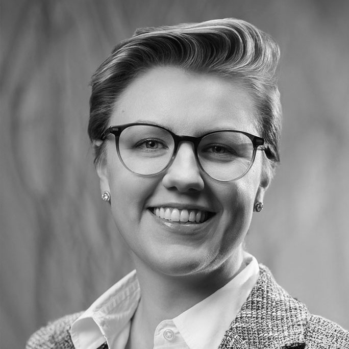 Black-and-white portrait of smiling professional wearing glasses