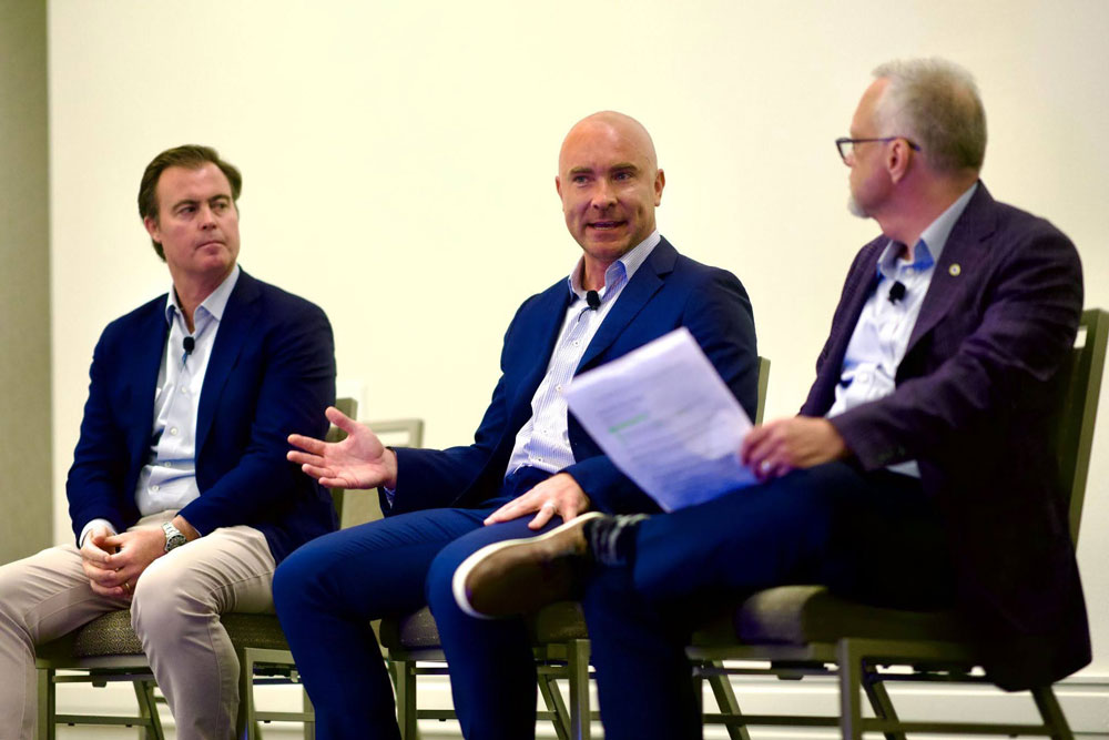 Three men in suits speaking on panel