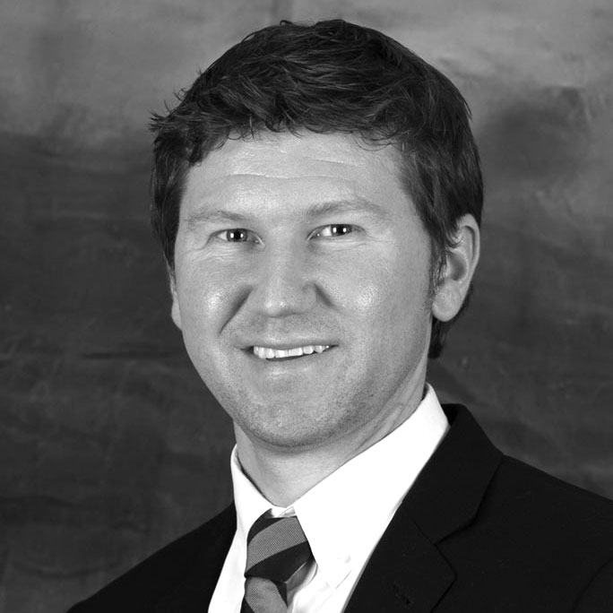 Black-and-white headshot of smiling man in suit
